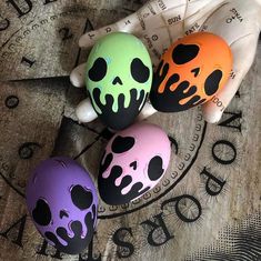 three painted skulls sitting on top of a wooden table next to a white glove and clock