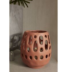 a pink vase sitting on top of a table next to a potted planter