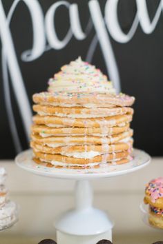 a stack of donuts sitting on top of a white plate next to a cake