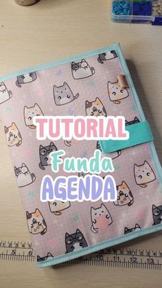 a small notebook with cats on it sitting next to some scissors and other crafting supplies