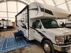 an rv is parked in a tent with a blue rug on the ground next to it