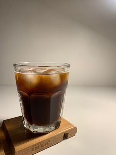 an iced beverage in a glass sitting on top of a wooden coaster