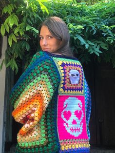 a woman wearing a colorful crocheted sweater with skulls on it