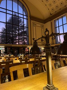 a table with two lamps on it in front of large windows and wooden chairs at the tables