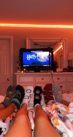 someone is laying in bed watching harry potter on the tv screen with their feet up