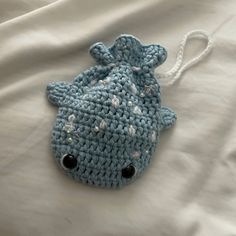 a blue crocheted bag sitting on top of a white bed cover covered in sheets