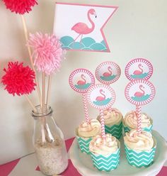 cupcakes with pink and blue frosting are on a plate next to some flowers