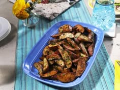 a blue plate filled with fried potatoes sitting on top of a table next to flowers