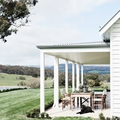 a black dog laying on the ground under a covered patio with white pillars and chairs