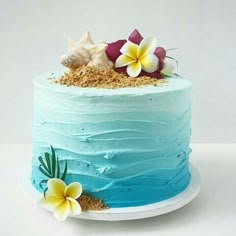 a blue cake with flowers and shells on top