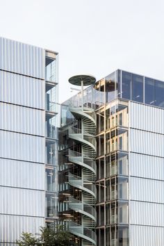 a tall building with a spiral staircase in front of it's glass walls and windows