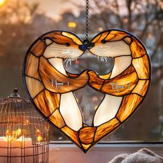 two cats in a heart shaped stained glass window hanging from a birdcage with the words love written on it