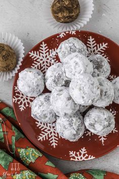 a red plate topped with snowball cookies next to cupcakes