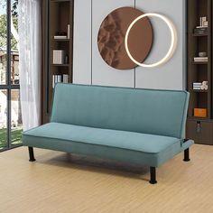 a blue couch sitting in front of a book shelf with a circular mirror on the wall