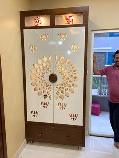 a man standing in front of a white and brown door with an intricate design on it