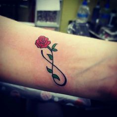 a rose tattoo on the arm with a musical note and a single flower in it