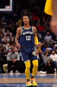 a basketball player with dreadlocks is on the court in front of an audience