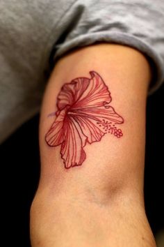 a woman's arm with a red flower tattoo on the left side of her arm