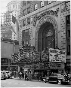 an old black and white photo of people standing in front of a theater