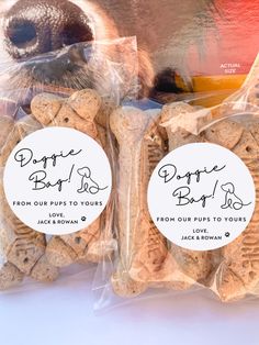 two bags of dog biscuits in front of a teddy bear's face and the label says doppie bag is for dogs from our pup to yours