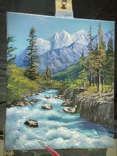 an easel with a painting of a mountain river