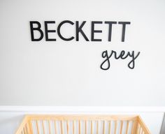 a baby crib in front of a white wall with the word bechett grey on it