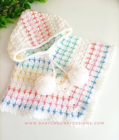 two crocheted baby blankets with pom - poms on them, one is white and the other is multicolored