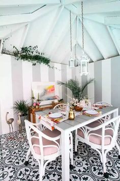 a dining room table set for four with pink chairs