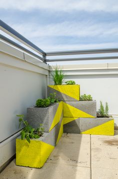 three cement planters with plants in them sitting on the side of a building next to a garage door