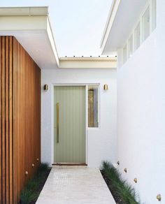 a white house with a green door and some plants