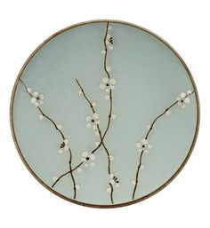 a glass plate with white flowers and branches on it's side, against a white background