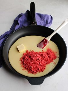 a pan filled with red food next to a spatula on top of a table