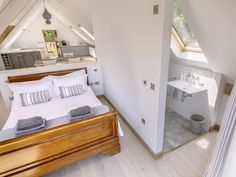 a bed sitting in a bedroom next to a bathroom under a slanted skylight