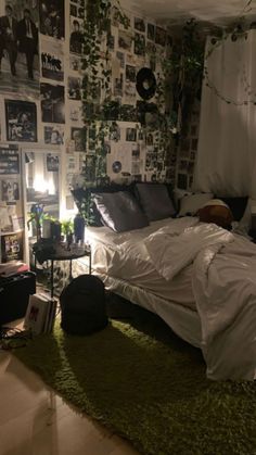 an unmade bed sitting in a bedroom next to a lamp and pictures on the wall