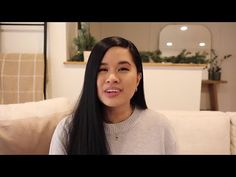 a woman with long black hair sitting on a couch