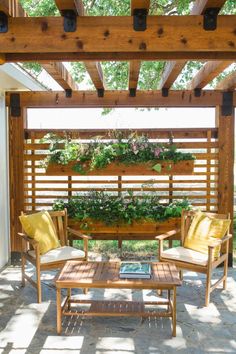 two chairs and a table under a pergolated area with plants growing on it