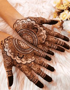 two hands with henna designs on them and flowers in the background, all around