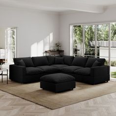 a living room with a large black couch and ottoman in the middle of the room