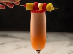 a person is holding up a drink with strawberries and lemons on it,