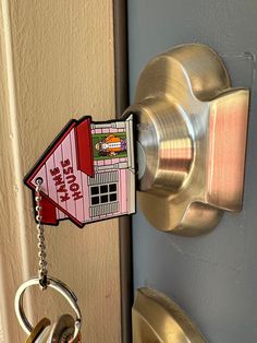 a house shaped keychain hanging from a door handle with a lock on it