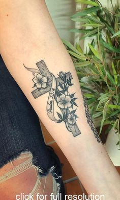 a woman's arm with a tattoo on it that has flowers and a ribbon