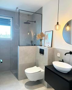a white toilet sitting next to a bathroom sink under a mirror on top of a counter