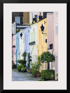 a row of colorful houses with potted plants on each side and one light hanging from the roof