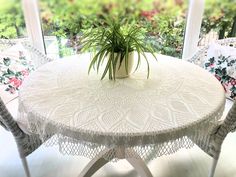 a potted plant sitting on top of a white table next to two wicker chairs