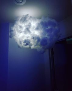 a cloud that is floating in the air with lights on it's sides and some clouds hanging from the ceiling