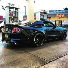 a black sports car parked in front of a gas station