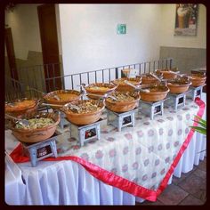 a table topped with lots of bowls filled with food next to a metal fenced in area