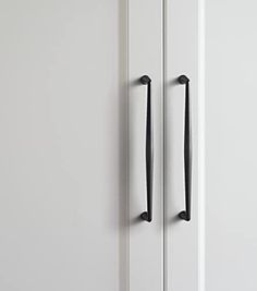 two black handles are on the white cabinet doors, one is open and the other is closed