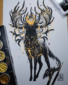 a drawing of a stag with gold and black ink on paper next to paintbrushes