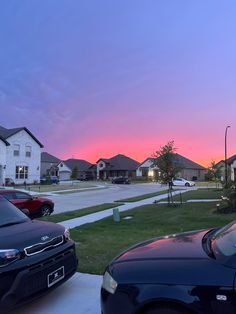 two cars parked in front of houses at sunset